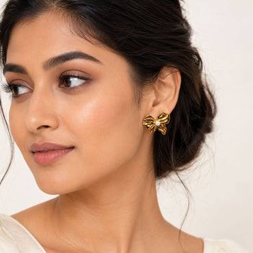 Close-up view of gold bow earrings with pearl centerpiece