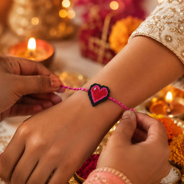 Pink braided thread rakhi with heart-shaped centerpiece