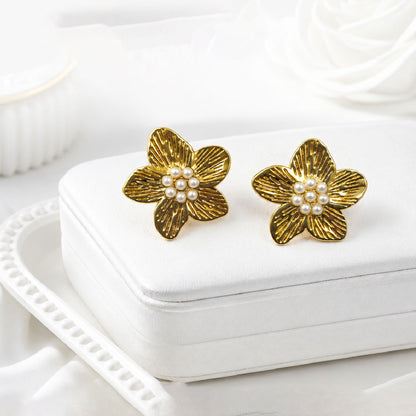 Detailed view of floral gold earrings with pearl cluster center