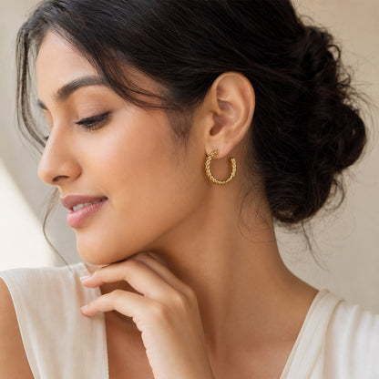Close-up view of gold hoop earrings with rope texture