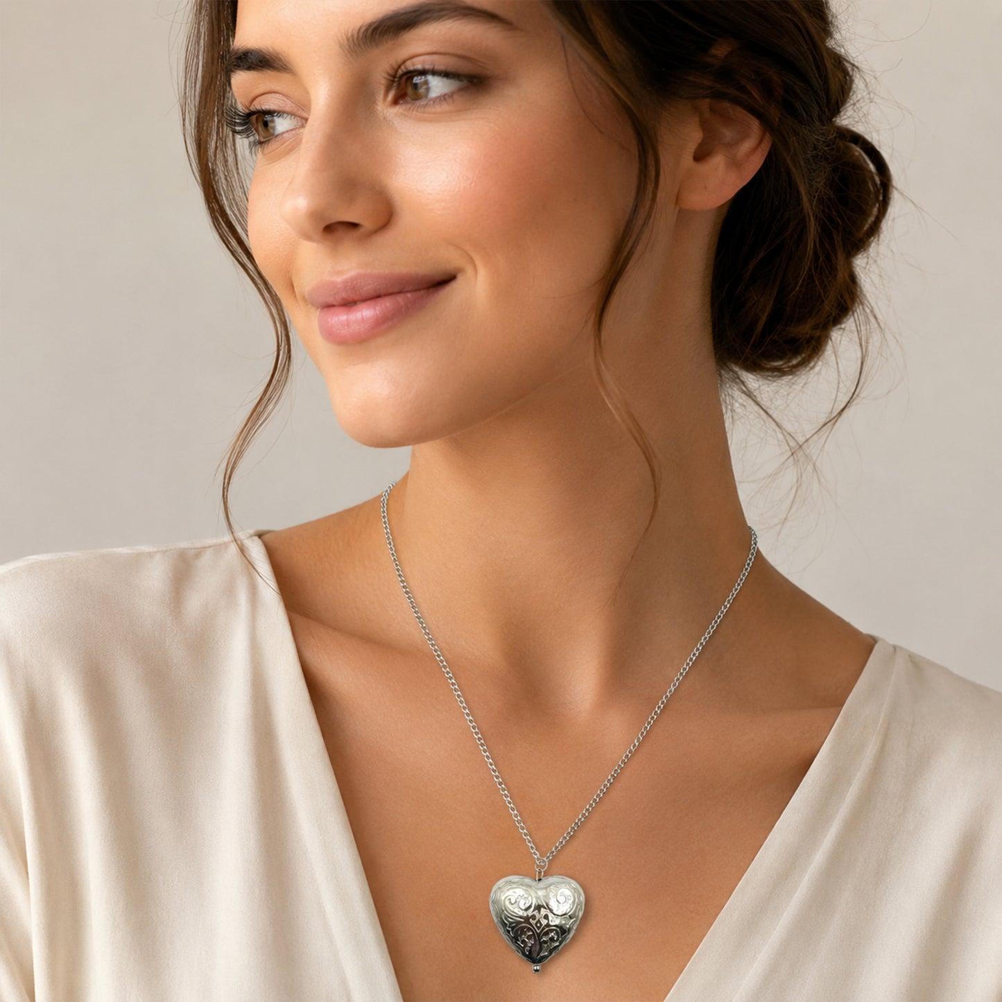 Close-up view of silver heart necklace with floral engraving