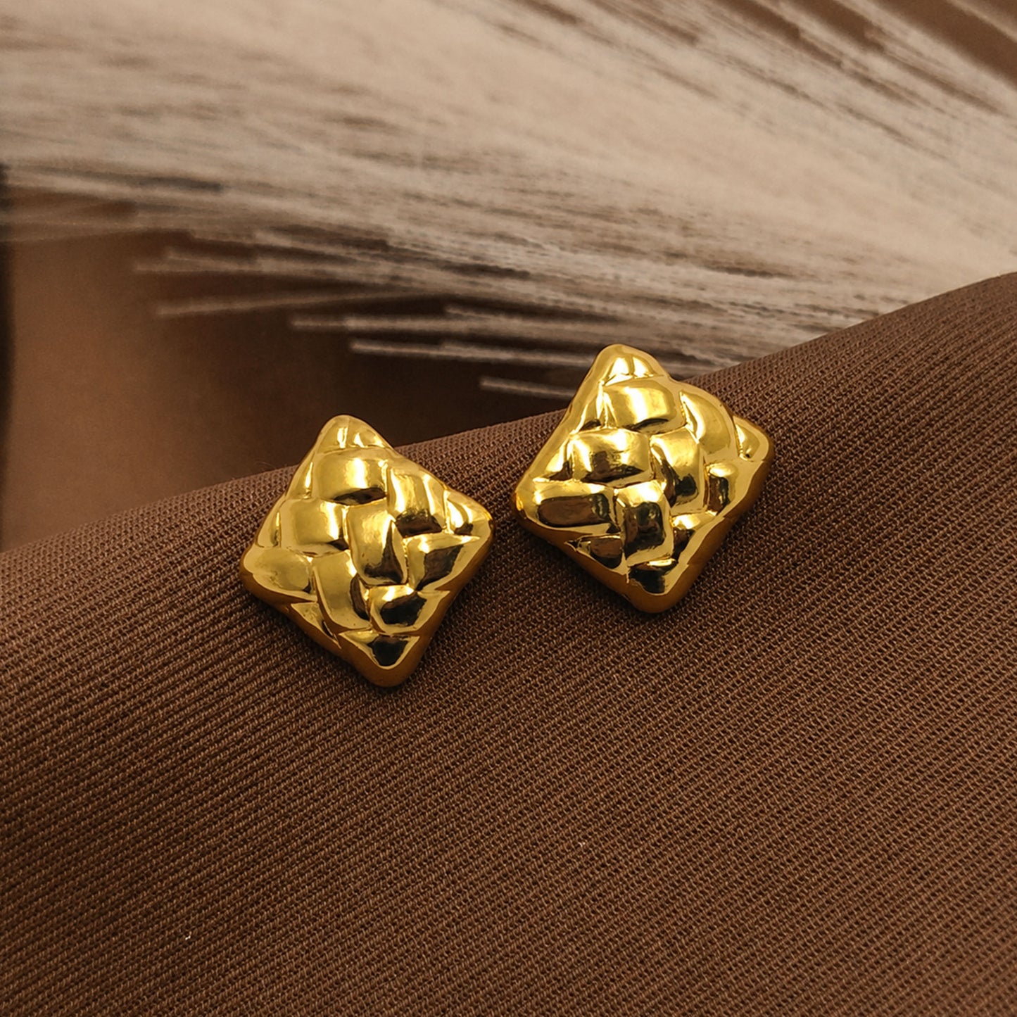 Detailed view of sculpted gold square stud earrings
