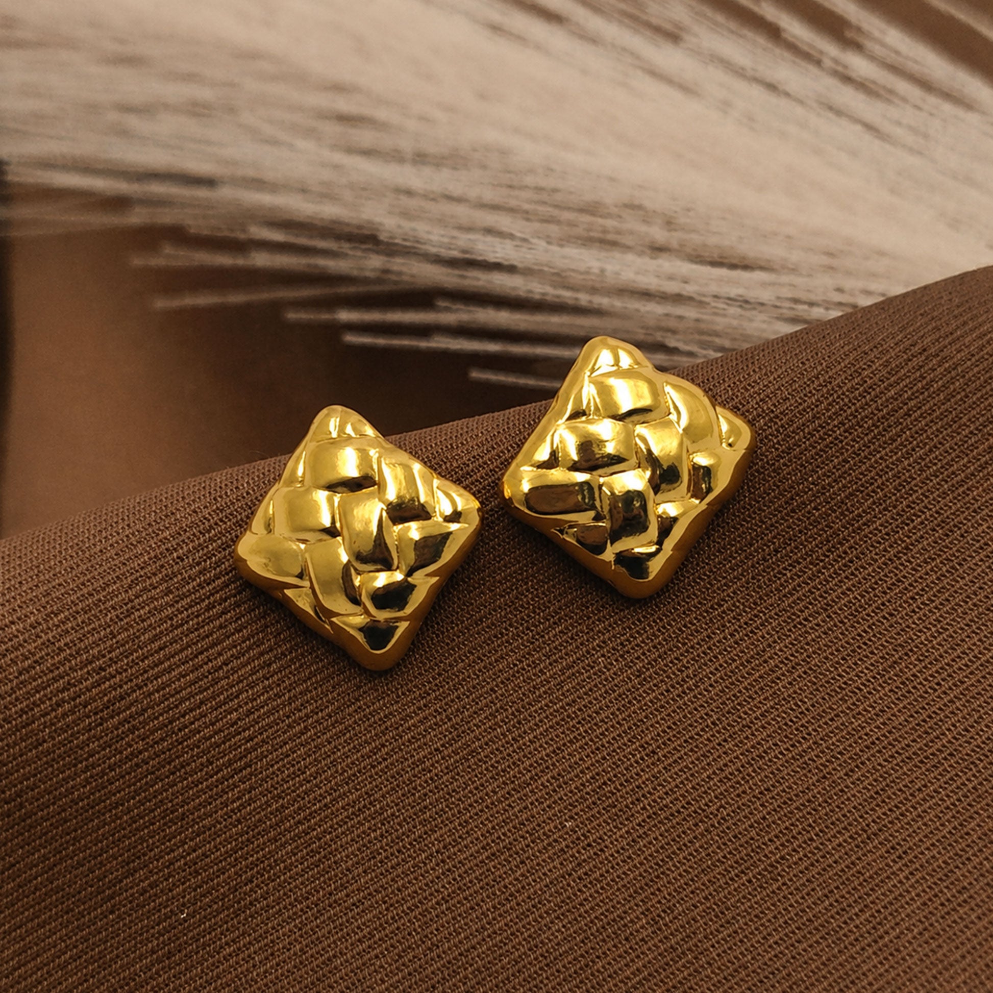 Detailed view of sculpted gold square stud earrings