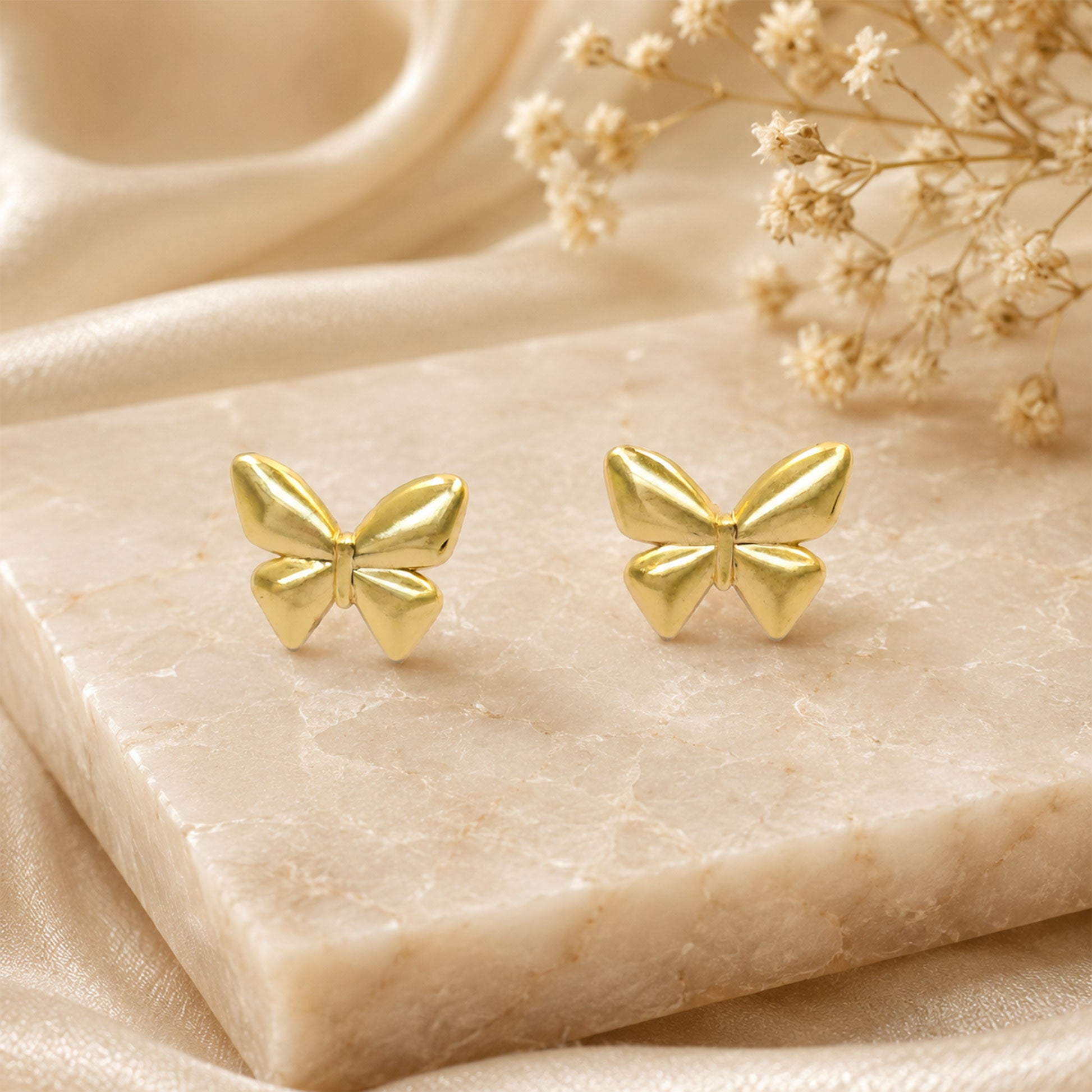 Detailed view of smooth gold butterfly stud earrings
