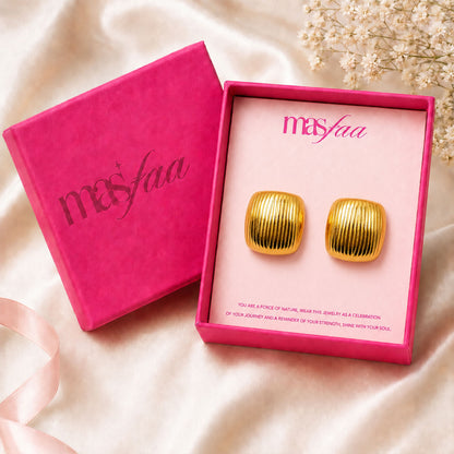 Detailed view of bold gold square dome stud earrings