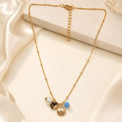 Detailed view of gold shell pendant with pearl and coin charms