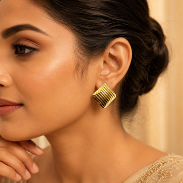 Woman wearing gold ribbed square stud earrings for elegant look